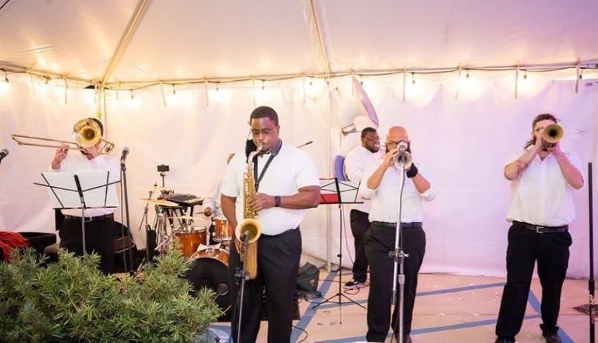 Brass band performing under a tent at an outdoor event